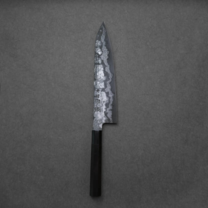 Damascus gyuto with a black handle and etched blade on a gray background