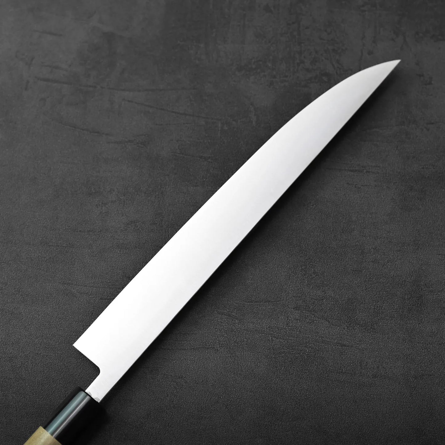 Sujihiki with saya resting, blade visible along the wooden cover, highlighting its slim, long form.