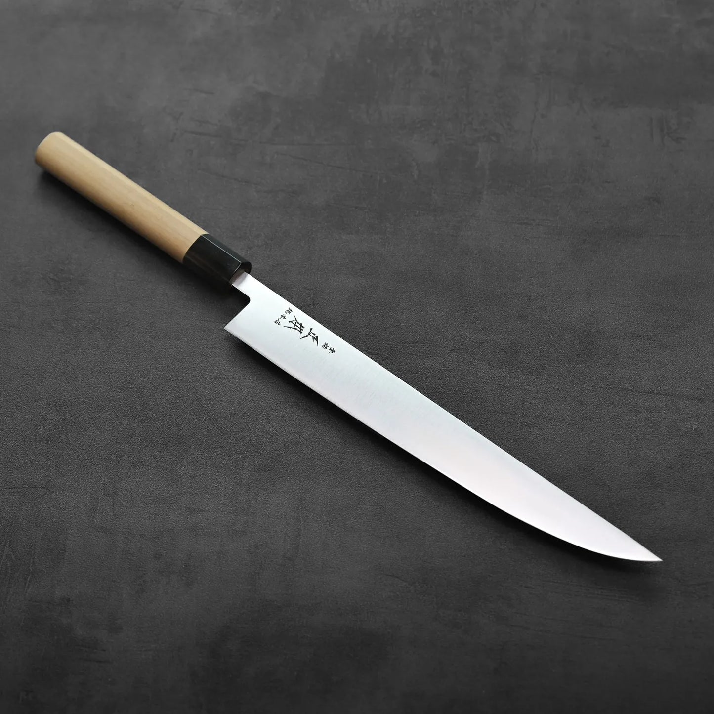 A sujihiki with a saya, showing clean lines and refined detailing on the blade and handle.
