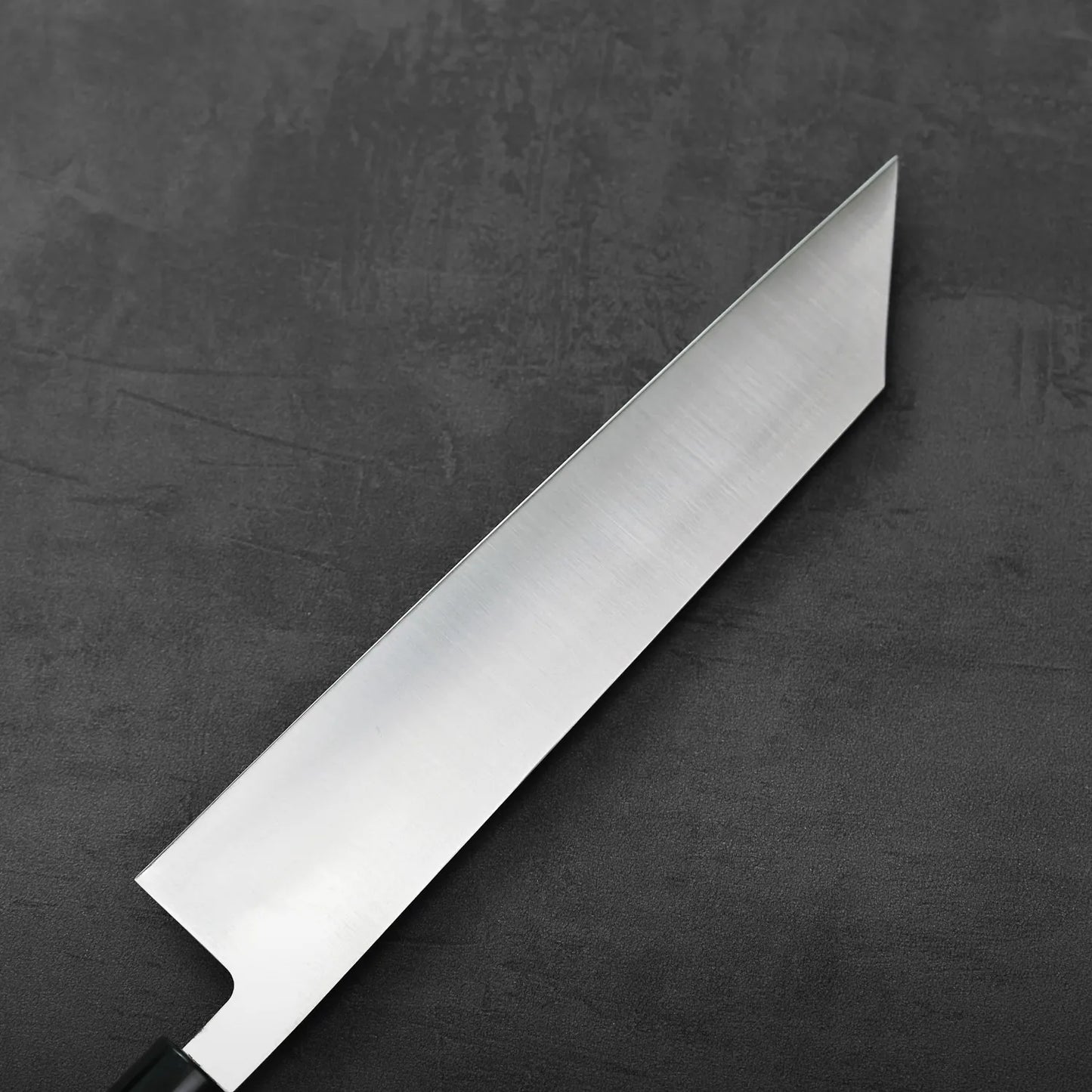 A close-up of a kiritsuke gyuto with saya, showing details of the blade and handle.