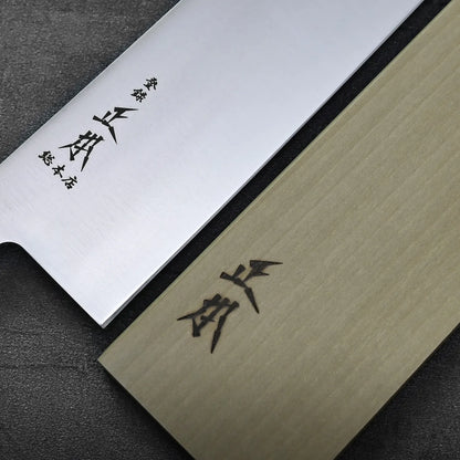 A close-up of a kiritsuke gyuto and saya, both displaying black Kanji characters.