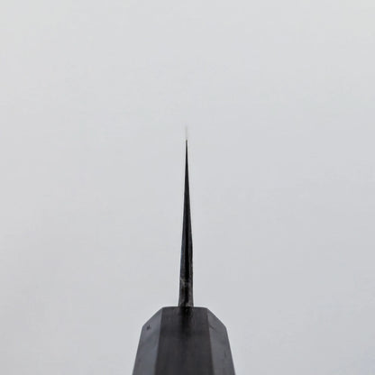 Choil shot of a knife viewed from the handle, with the blade positioned vertically against a plain white background.