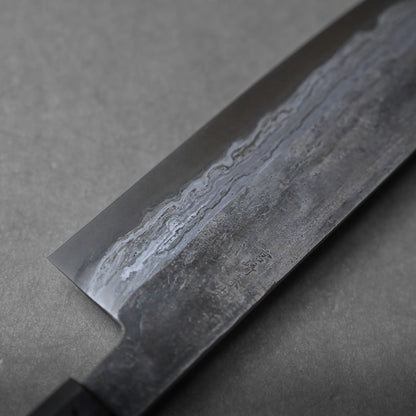 A close-up view of a Japanese chef’s knife displays intricate patterns on the blade, emphasizing traditional Damascus steel craftsmanship, set against a plain grey background.