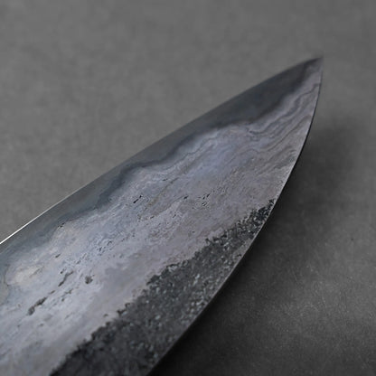 A close-up view of the pointed tip of a Miyazaki rentetsu gyuto blade, showing detailed patterns and textures in the steel against a plain gray background.