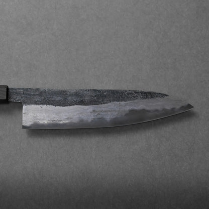 A close-up of a Japanese-style Miyazaki rentetsu gyuto chef’s knife with a dark, textured handle and a tapered blade, set against a gray, textured background.