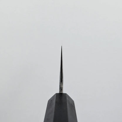 Choil shot of a knife blade, photographed from above, with the edge facing upward against a plain, light gray background.