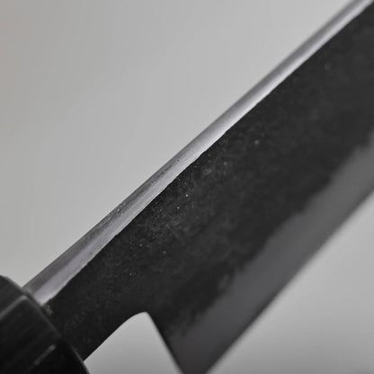 Close-up of the spine finish of the gyuto knife against a plain background.