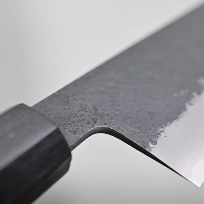 Close-up view of the choil finish of a kiritsuke gyuto knife against a plain background.