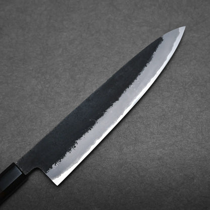 A close-up of a Japanese chef's knife with a dark handle and shiny blade set against a textured gray background.