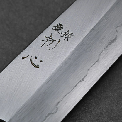 Close-up of vertically engraved kanji characters on a santoku knife blade; photographed to emphasize engraving detail and steel surface.