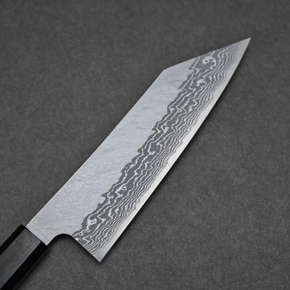 A close-up of the Nigara tsuchime damascus VG10 bunka 180mm knife, showing its tsuchime damascus blade pattern as it rests on a textured dark gray surface.