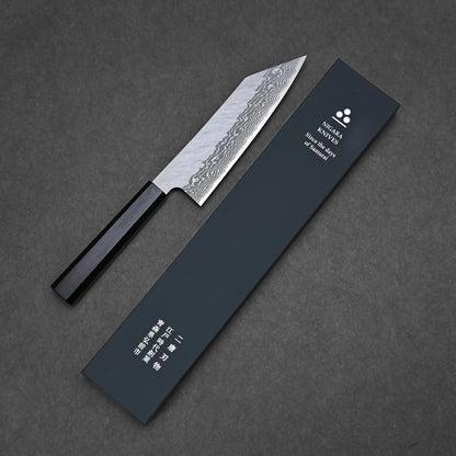 The Nigara tsuchime damascus VG10 bunka 180mm, featuring a patterned blade and dark handle, is displayed beside a dark blue Nigara Hamono box with Japanese and English text on a textured dark surface.