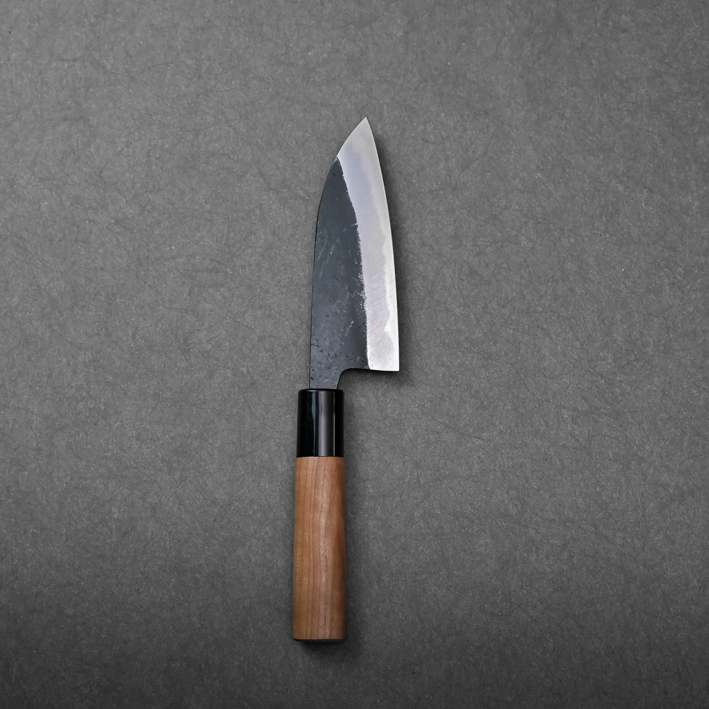 Wooden-handled Japanese knife with a visible angled dark blade; the shape suggests it is a petty knife.
