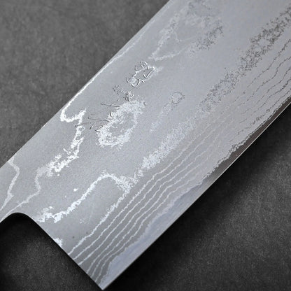 Wavy Damascus pattern and engraved Japanese characters on the flat edge of a Japanese knife, likely a nakiri.