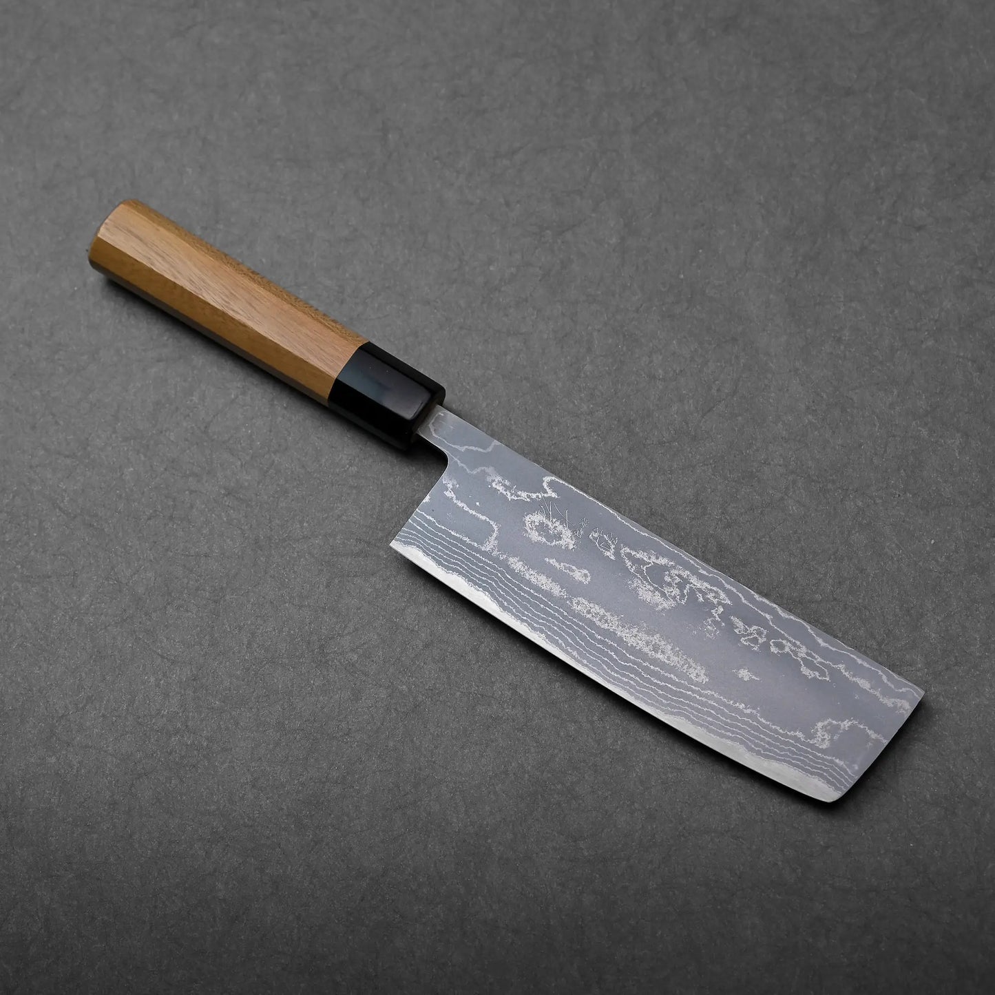 A rectangular-bladed Japanese knife with a wooden handle and a patterned steel finish, identified as a nakiri.
