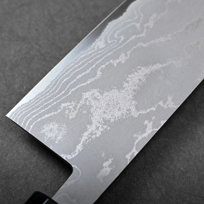 Blade close-up showing a Japanese knife with a straight edge and rounded tip, featuring wavy Damascus patterns.