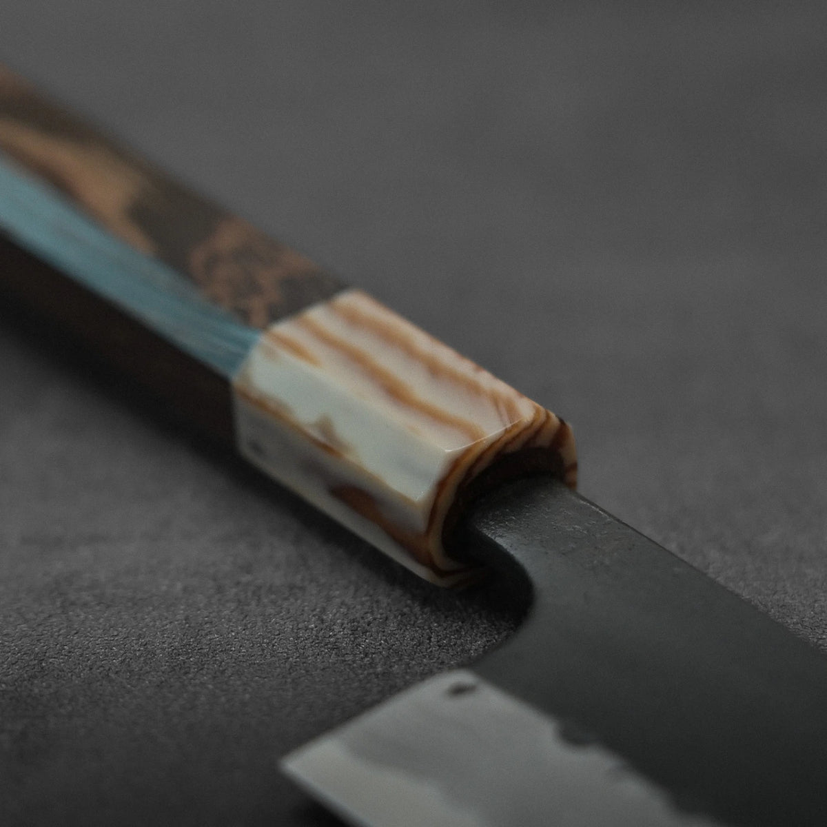Close-up of gyuto with marbled handle, damascus pattern visible on blade.