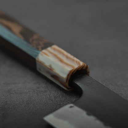 Close-up of gyuto with marbled handle, damascus pattern visible on blade.