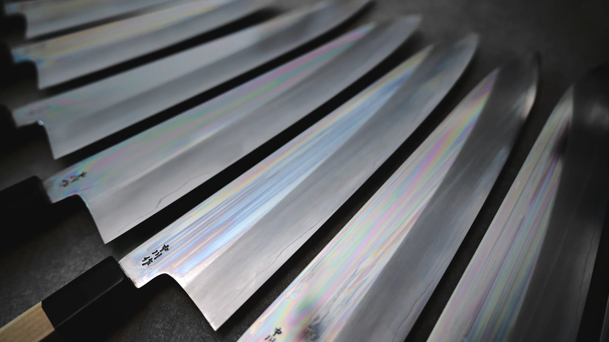 Mirror-polished Nakagawa ginsan gyuto knives arranged in a row, showing off their polished blade faces and kanji engravings.