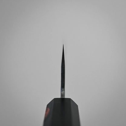 Choil shot of a workhorse gyuto blade, centered against a plain, light gray background. The knife's handle is partially visible at the bottom of the image.
