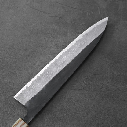 A gyuto with a kurouchi damascus finish is displayed, highlighting its blade and handle details.