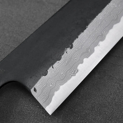 Gyuto blade close-up featuring damascus steel with a distinct wavy pattern on the surface.