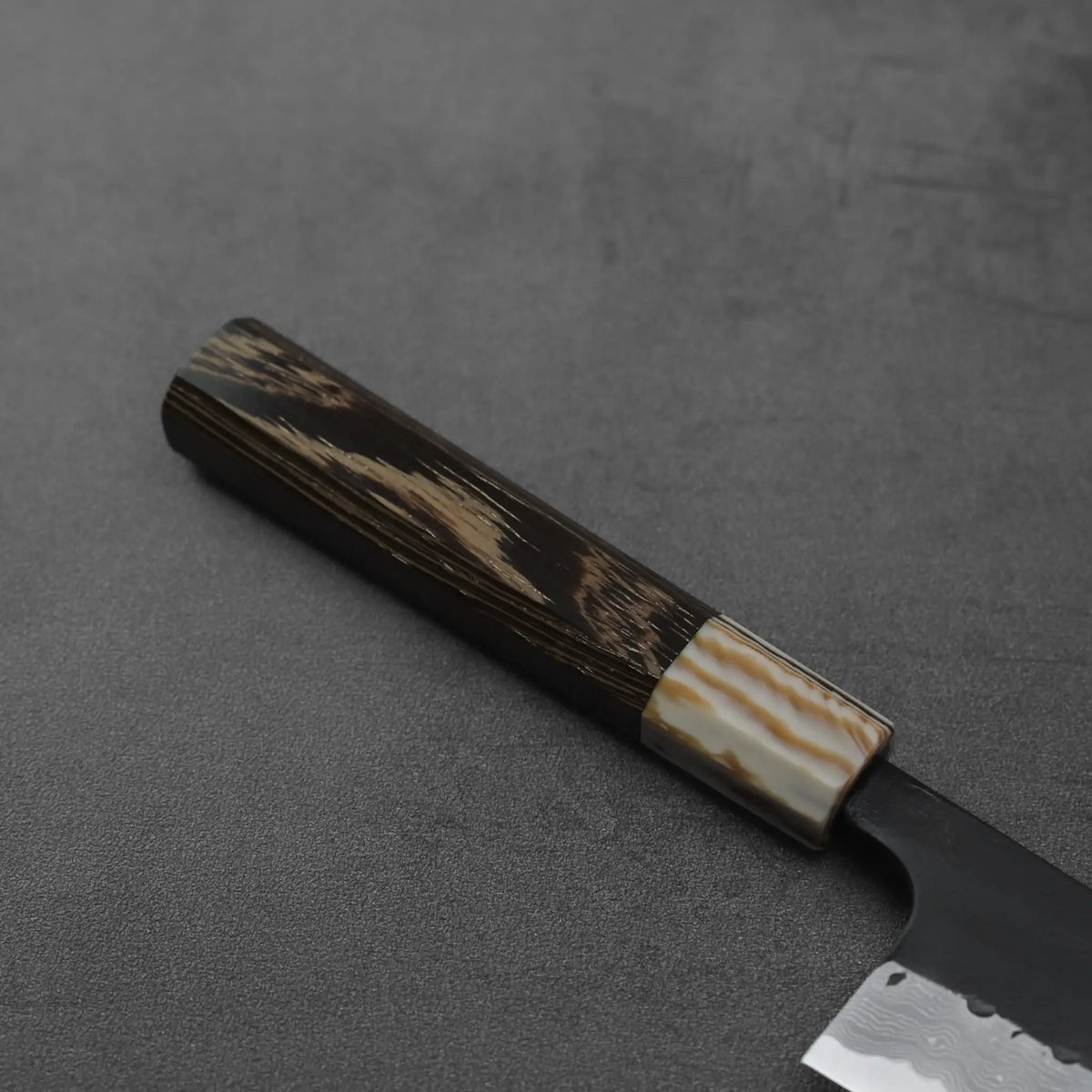 Gyuto handle in close-up, made of wood and resin, showing detailed texture and color patterns.
