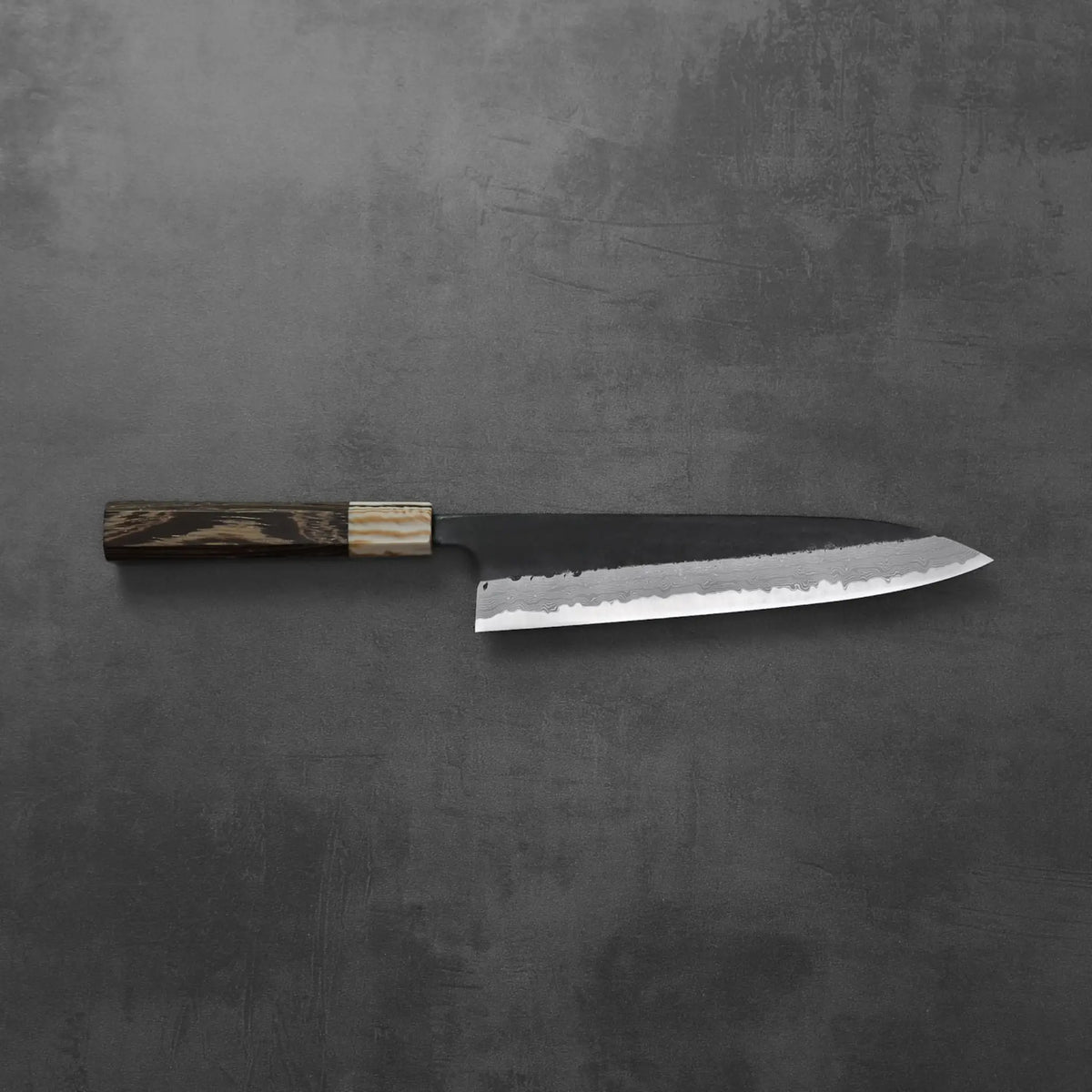 A gyuto with a wood handle, featuring damascus pattern and kurouchi finish.