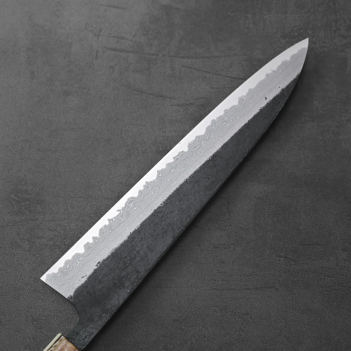 Gyuto with a patterned damascus blade, showing kurouchi finish and distinctive layered steel design.