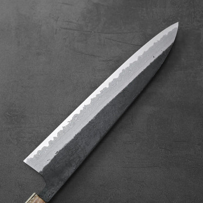 Gyuto with a patterned damascus blade, showing kurouchi finish and distinctive layered steel design.