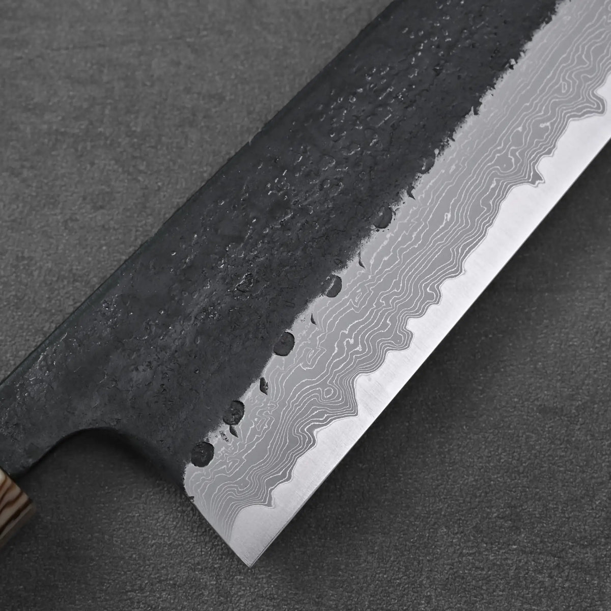 Gyuto with a wooden handle shown in close-up, highlighting its blade and textured grip detail.