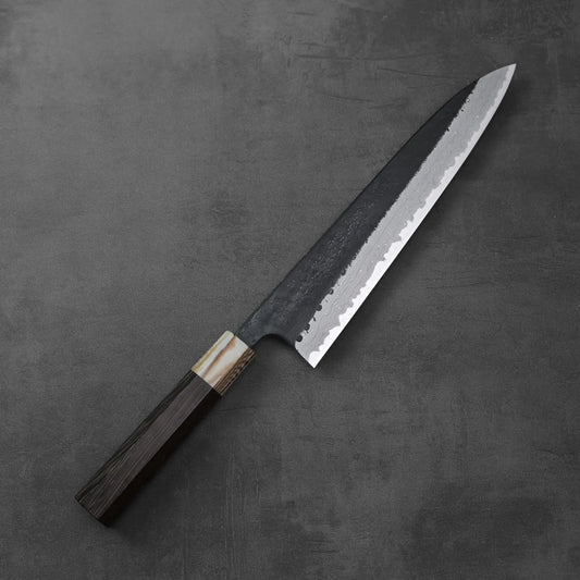 Gyuto with a dark handle, damascus-patterned blade visible, positioned alone.
