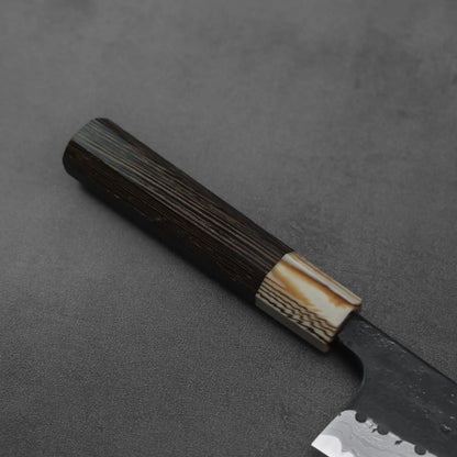 Gyuto handle in close-up: dark wood with a light accent, showing contrasting tones and clear wood grain.
