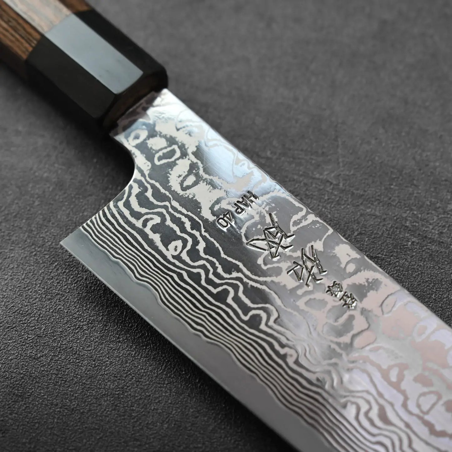 Close-up of a gyuto with etched damascus patterns, showing detailed texture and wavy lines on the blade.