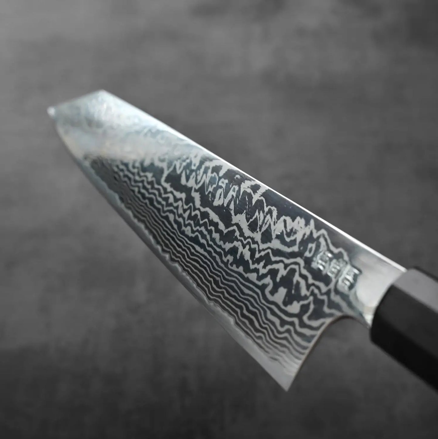 Kiritsuke gyuto with a 270mm blade, featuring a wavy Damascus pattern in a close-up detail view.