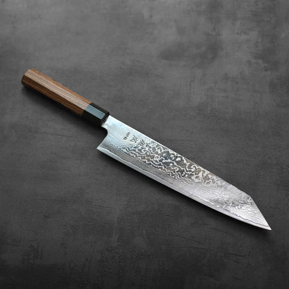 Kiritsuke gyuto with a damascus blade and wooden handle, emphasizing layered steel and wood grain detail.