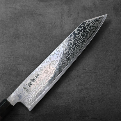 A close-up of a kiritsuke gyuto featuring wavy damascus patterns on the blade.
