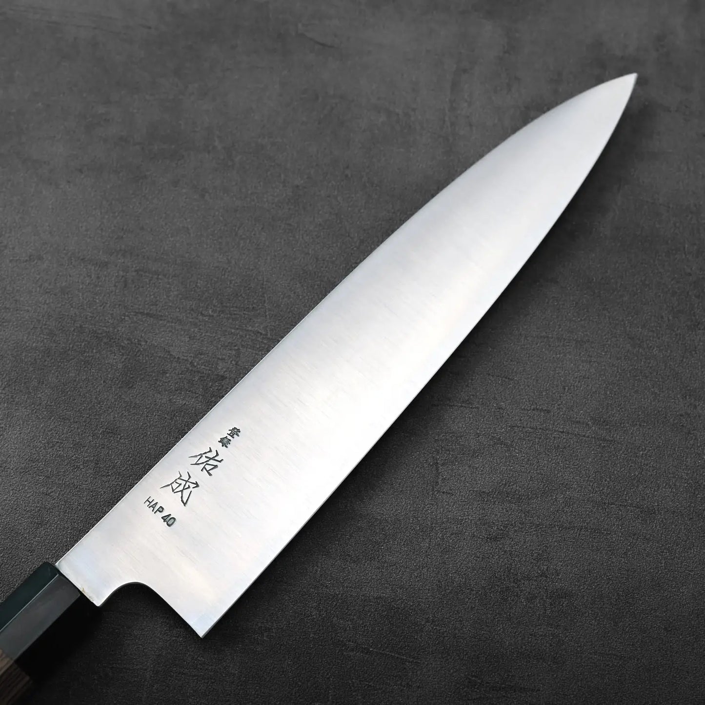 Gyuto with a silver blade and black handle, highlighting the contrast between the polished steel and grip.