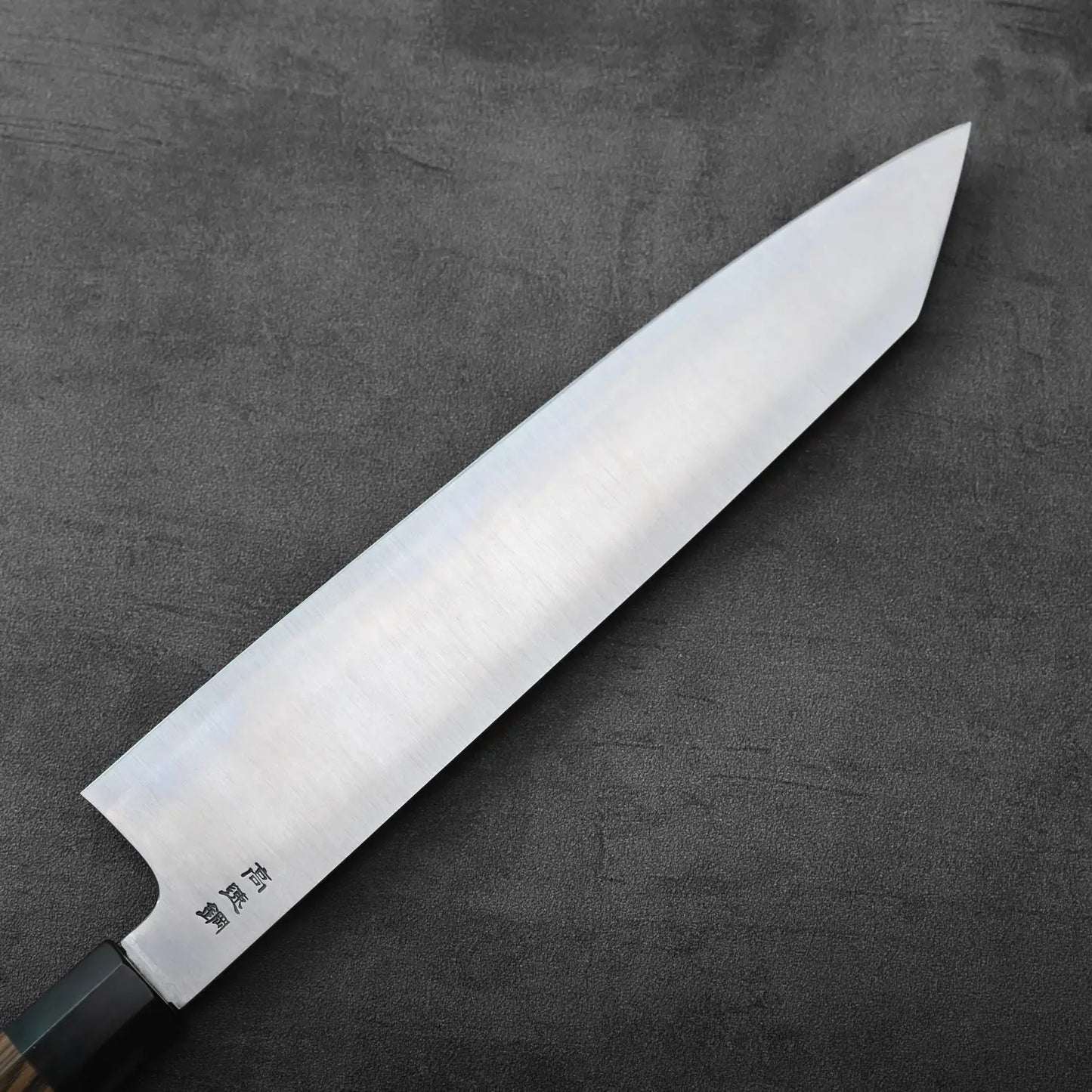 A kiritsuke gyuto with a 270mm blade is resting, displaying its profile and cutting edge.
