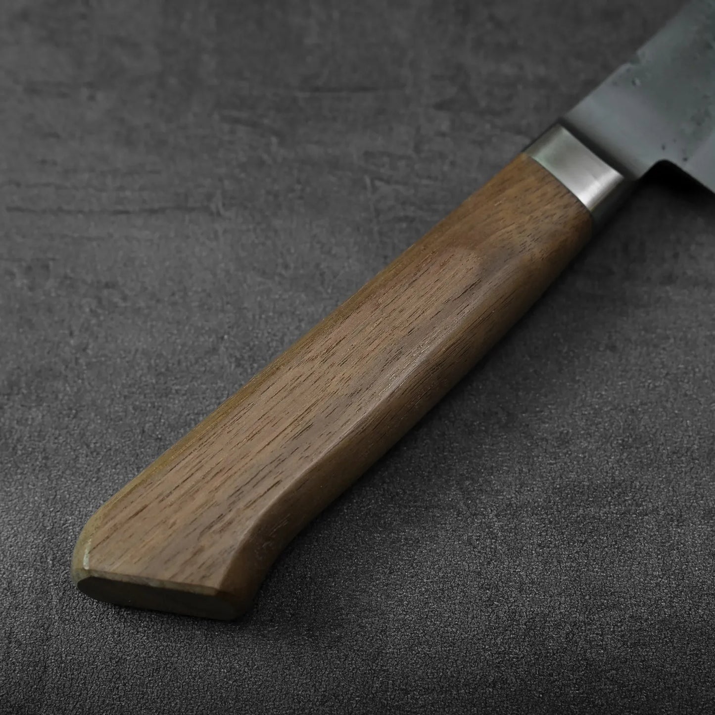 A close-up of a honesuki with a wooden handle, blade featuring nashiji finish and blue steel core.