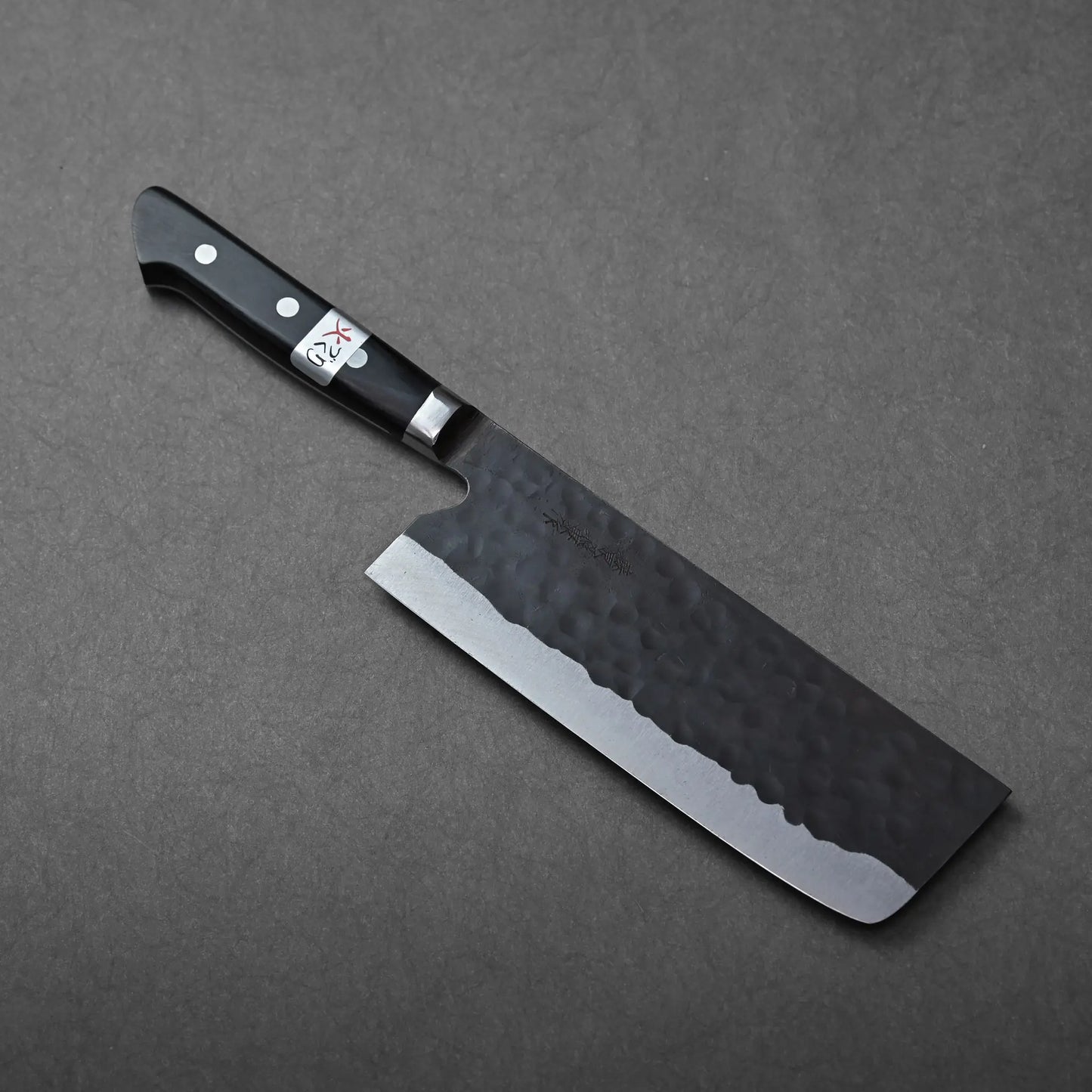 Nakiri with a hammered blade, shown resting and highlighting its unique textured metal and classic profile.