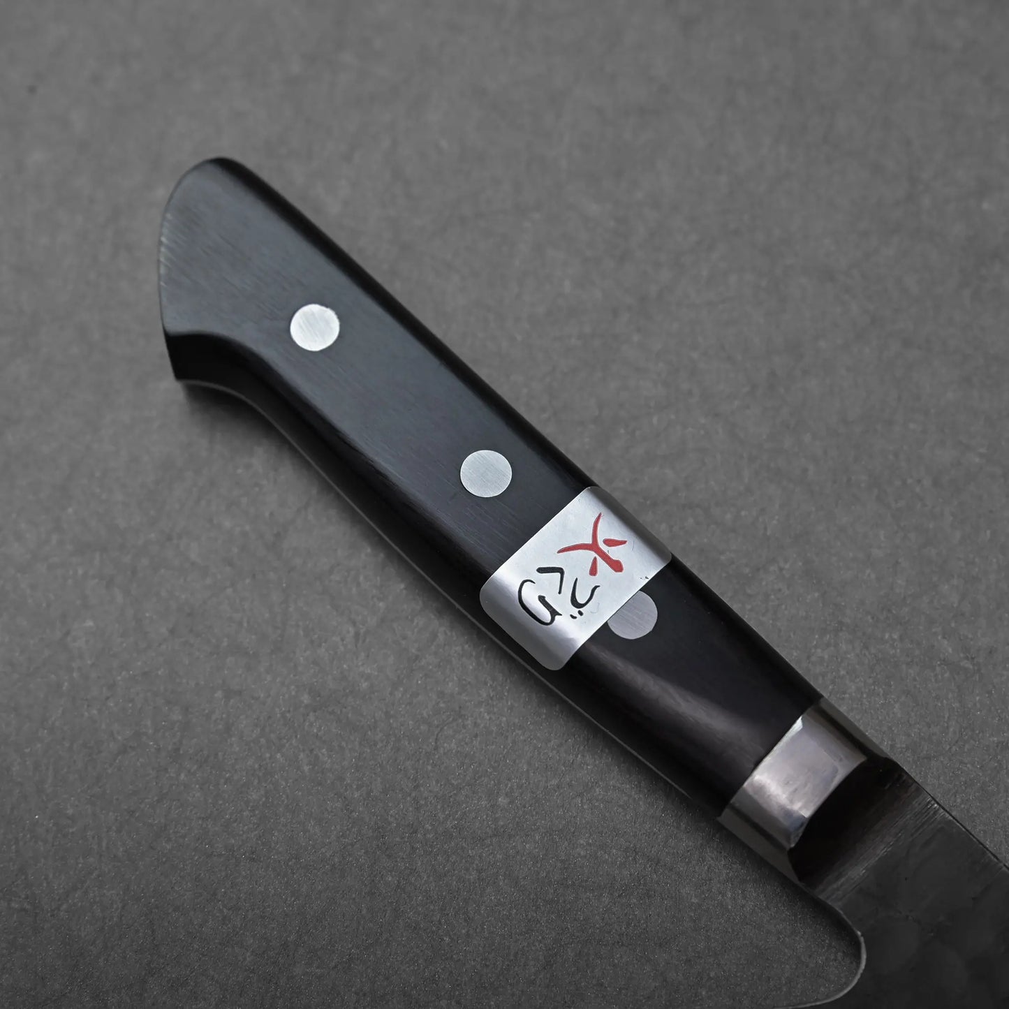 Nakiri handle close-up with two rivets and a silver Fujiwara label, showing detailed construction.