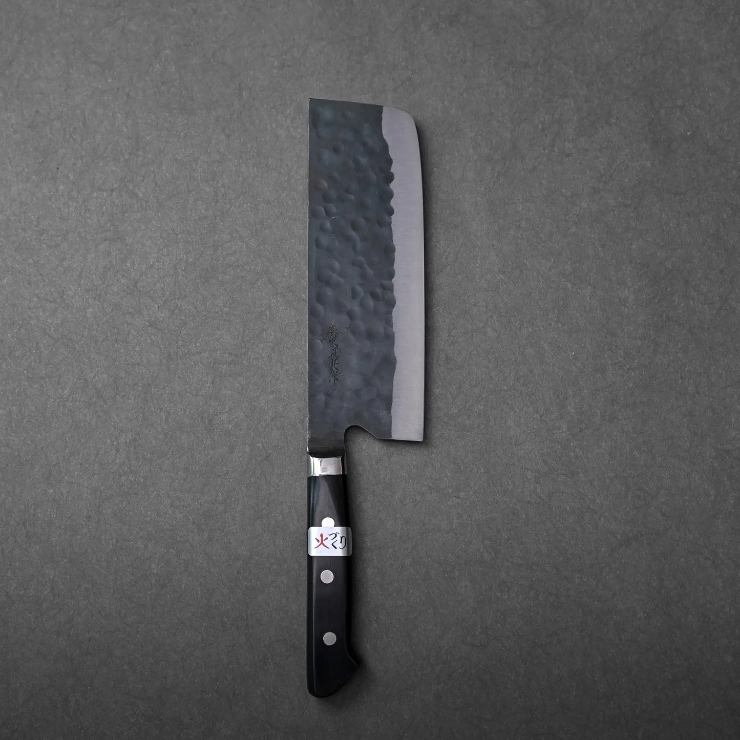 Nakiri with a dark hammered blade and black handle.