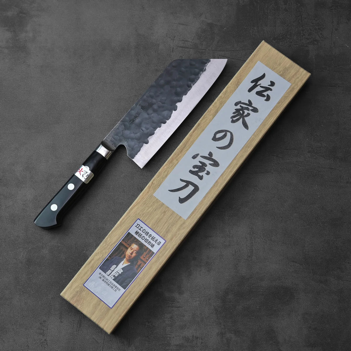 A bunka with a black handle sits next to a box featuring Japanese writing.