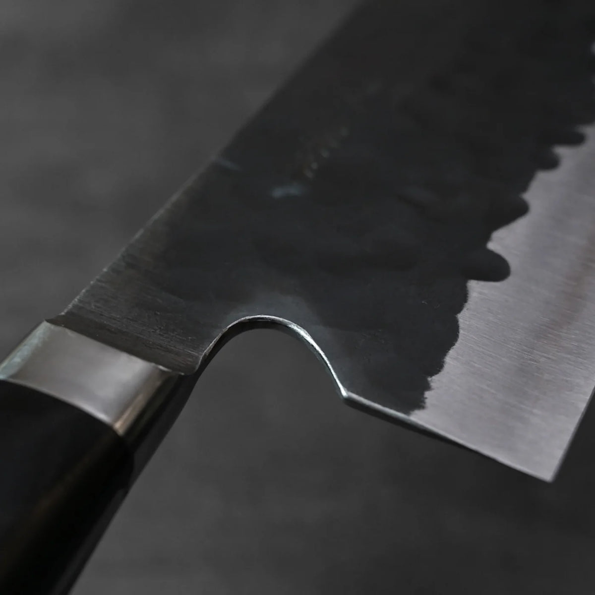 Bunka with hammered blade and dark handle in a close-up, showing distinctive tall blade profile.
