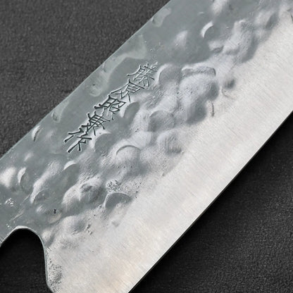 Santoku blade in close-up, featuring Japanese engraving on hammered steel.