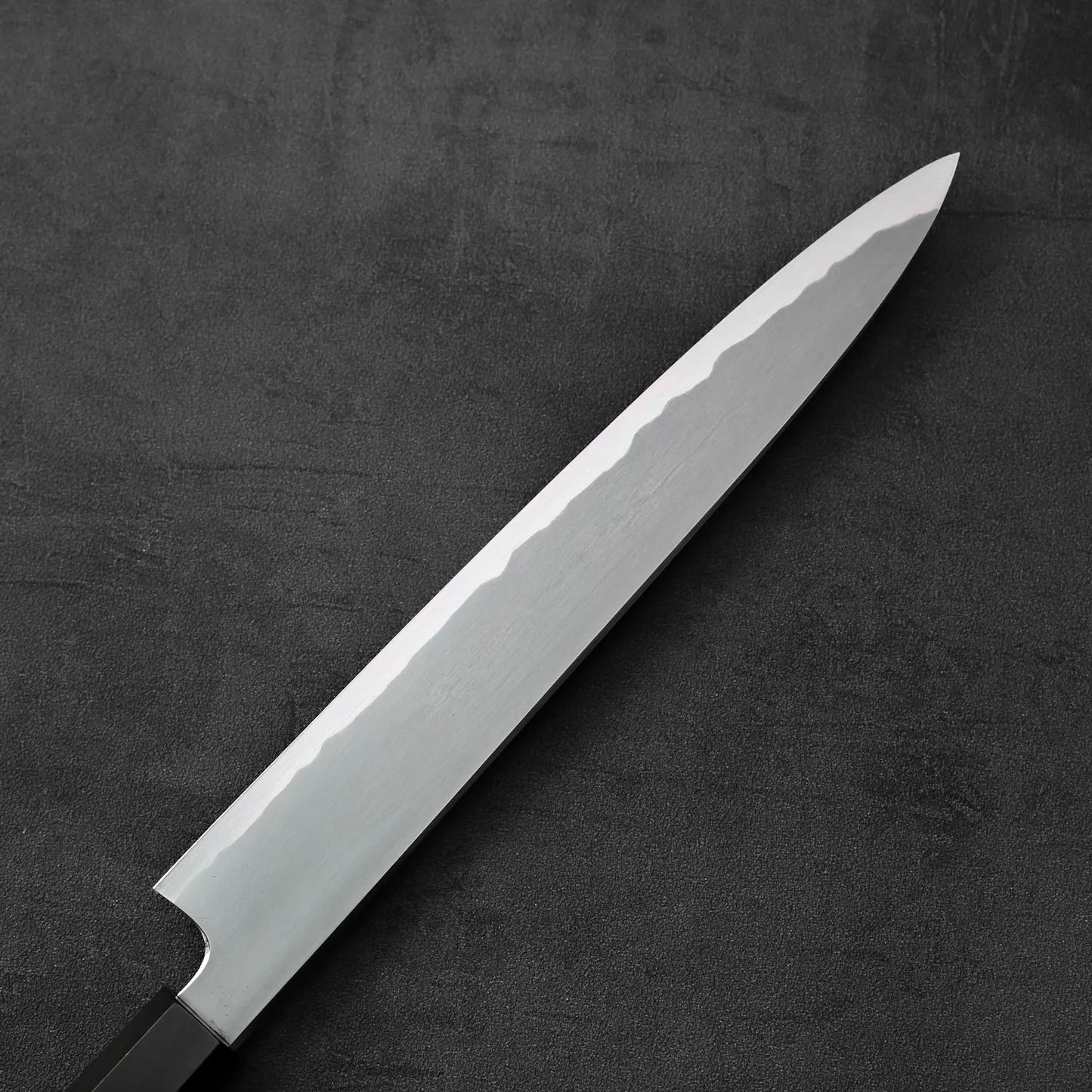 Sujihiki knife with a single edge, positioned to show the blade and handle details.