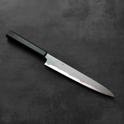 Sujihiki with a black handle is shown, highlighting the handle shape and details against a dark background.