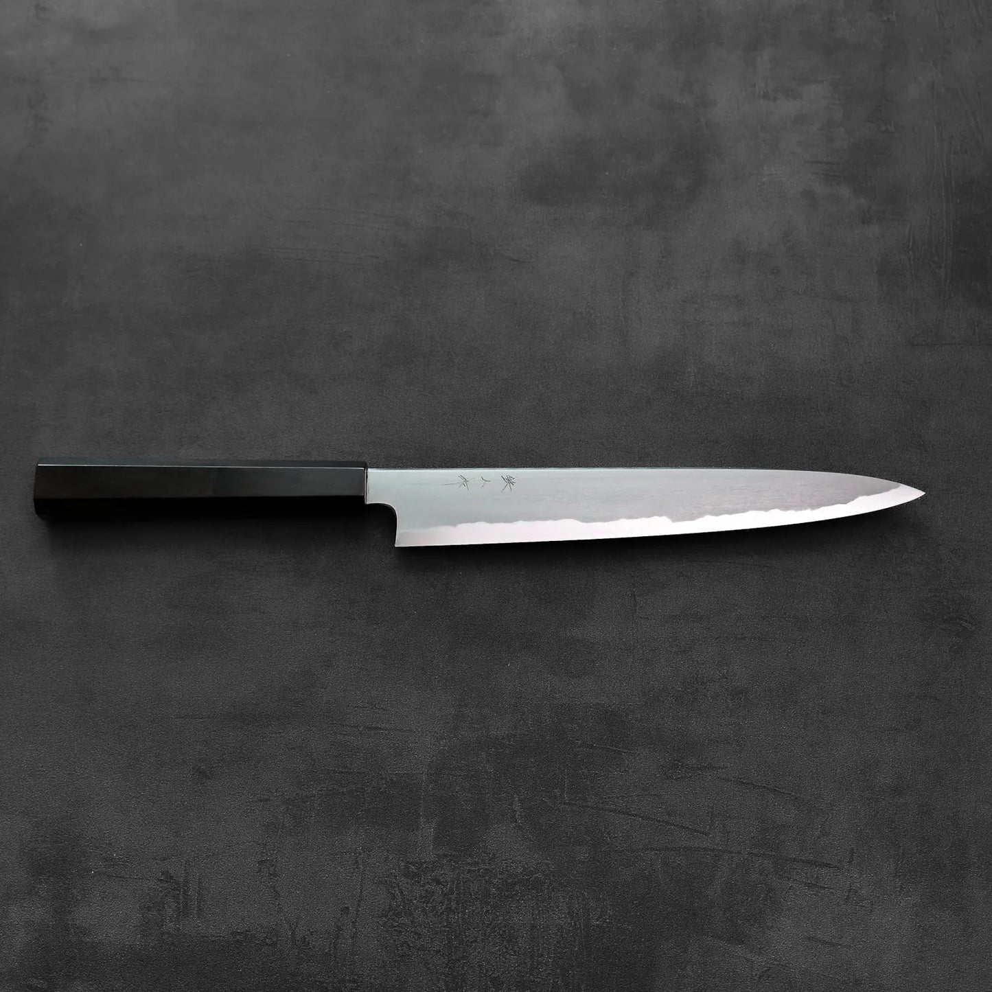 Sujihiki knife with a dark handle, resting with the blade exposed.