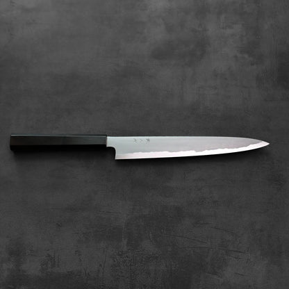Sujihiki knife with a dark handle, resting with the blade exposed.
